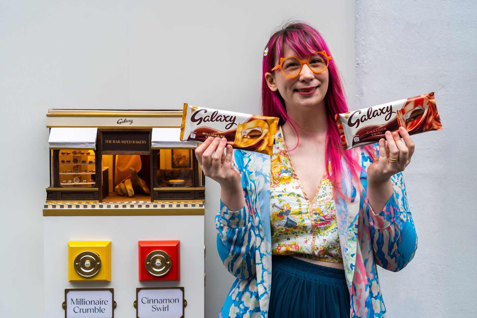 Kim-Joy holding the two Galaxy bars beside the bakery