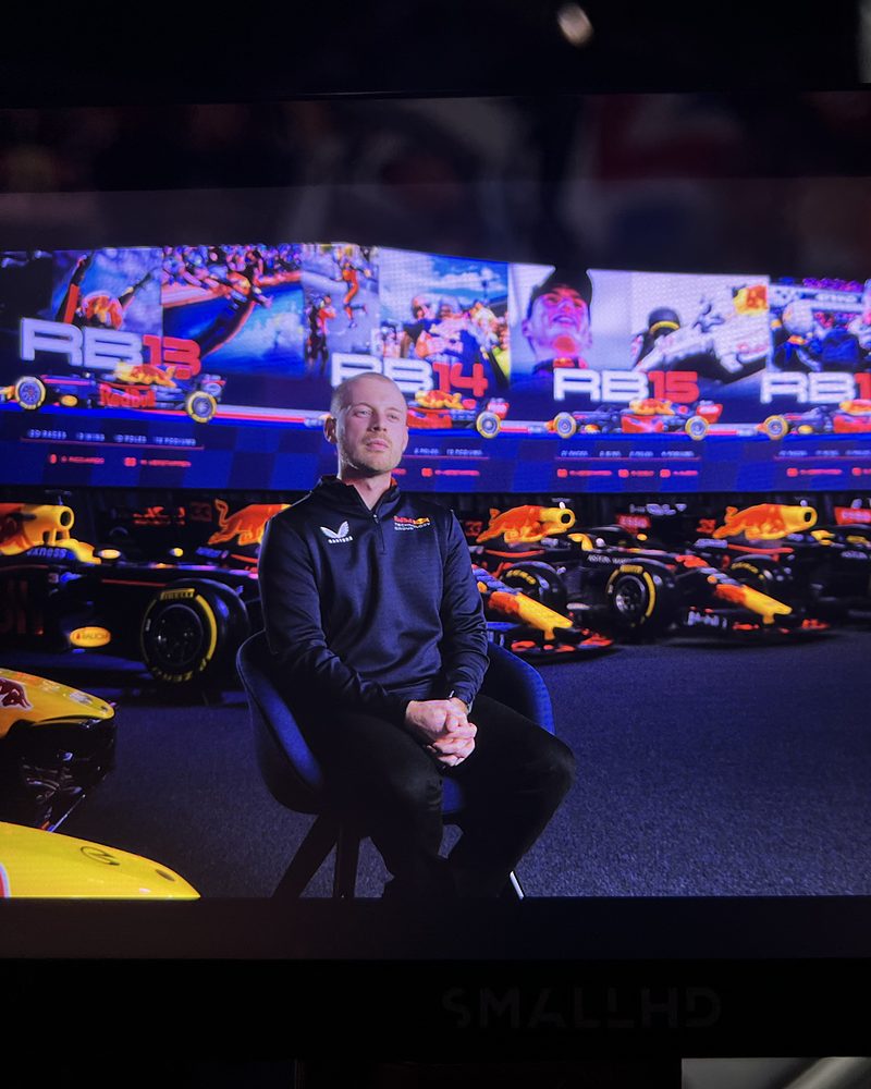 The shot on the monitor: an interviewee lit in front of the historic cars and the screen wall
