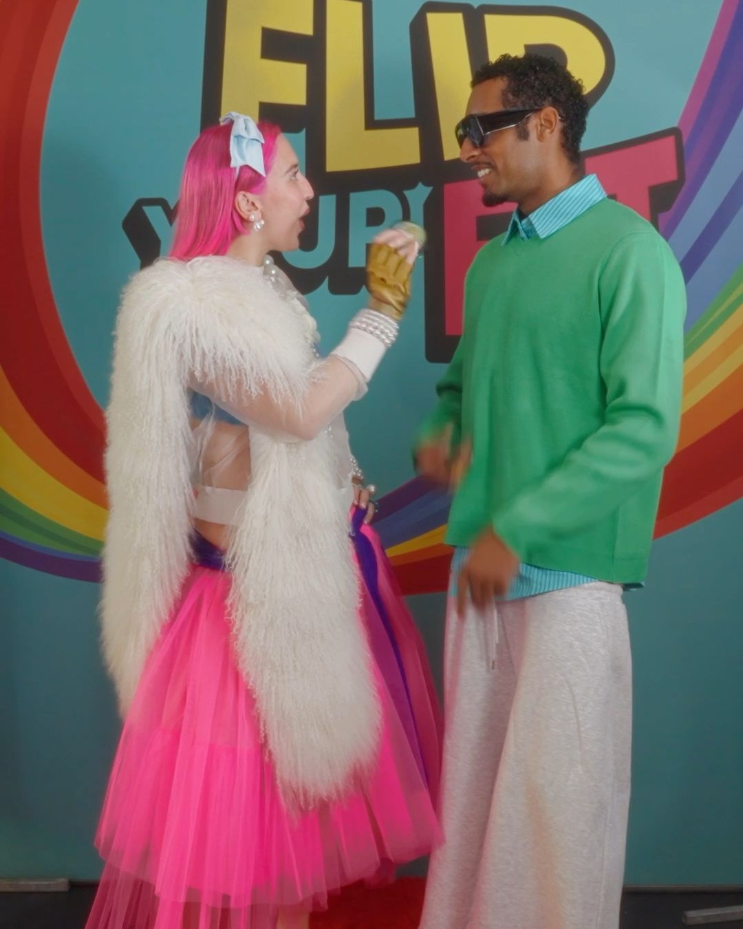 Abigale Masters with a guest in a green jumper in front of the Flip Your Fit wall